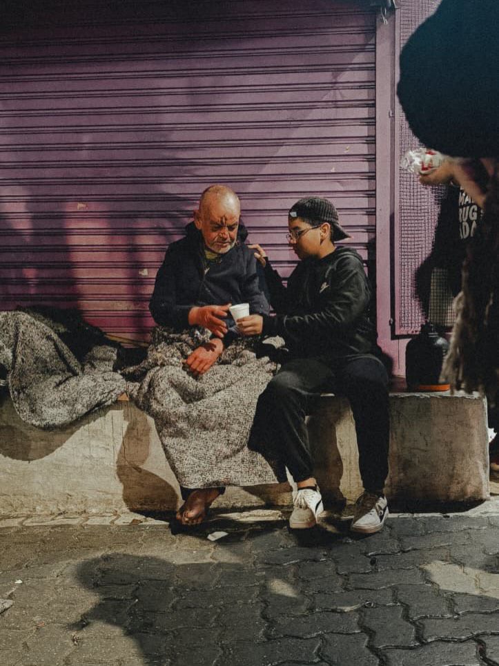 Voluntária conversando lado a lado com pessoa em situação de rua