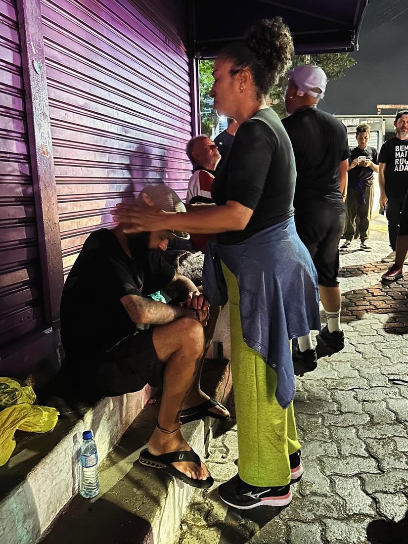 Voluntários entregando doações a pessoa em situação de rua