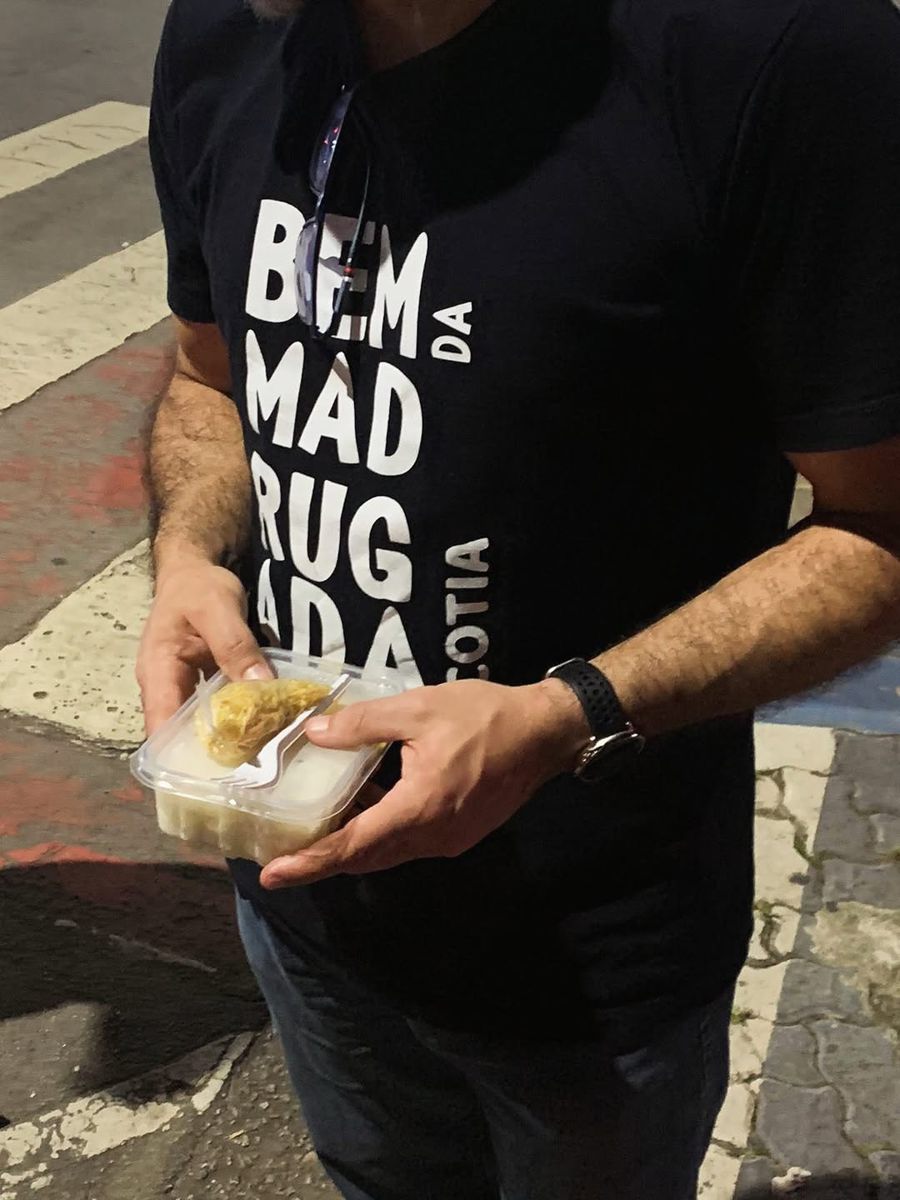 Voluntário com camiseta do projeto segurando marmita para entrega