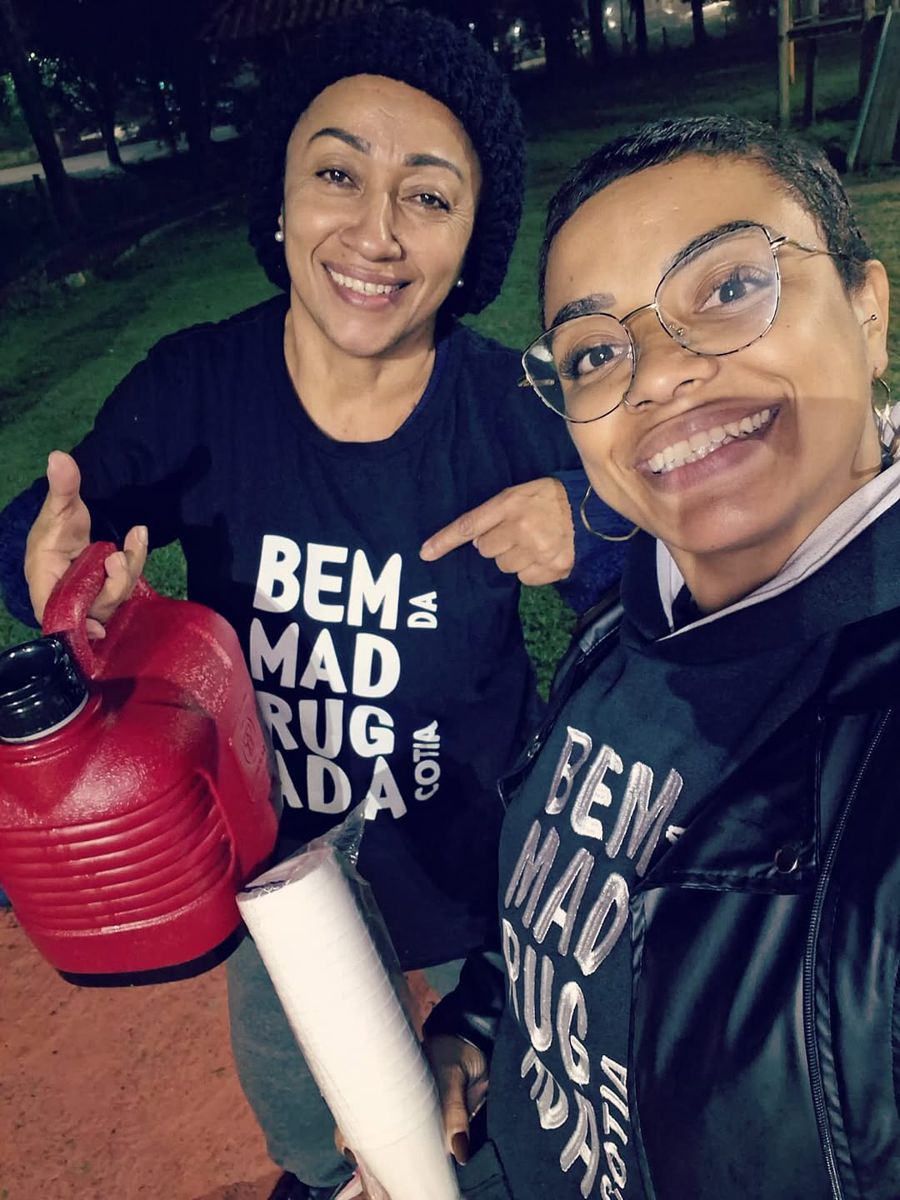 Duas voluntárias sorrindo com garrafa térmica de chocolate quente